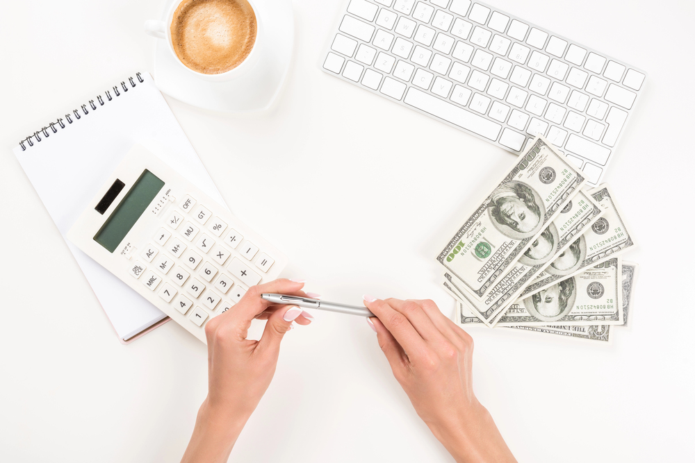 Front desk counting cash beside a calculator, representing missed copay and deductible collection