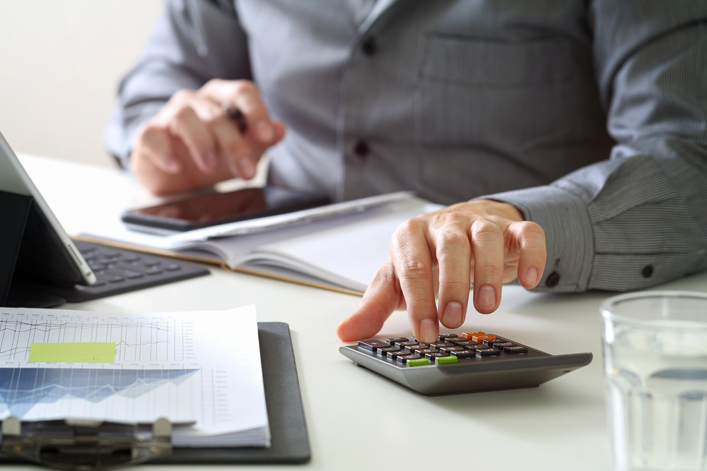 Office staff reviewing charts and using a calculator to verify insurance eligibility